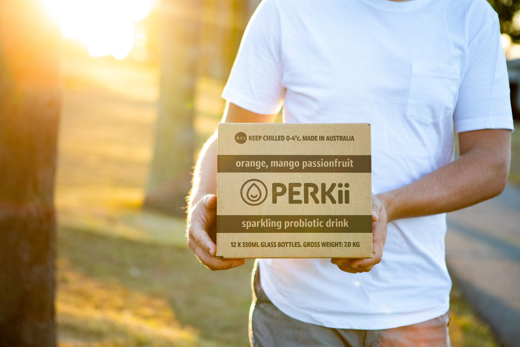 Young man holding box of PERKii Sparkling Probiotic Drink